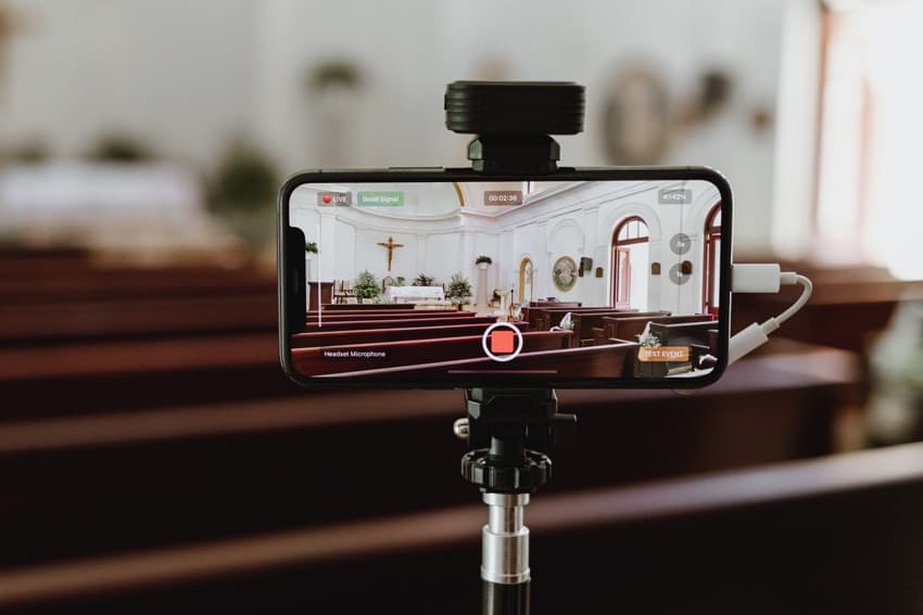 A phone on a tripod running a test stream in the EventLive app inside an empty church